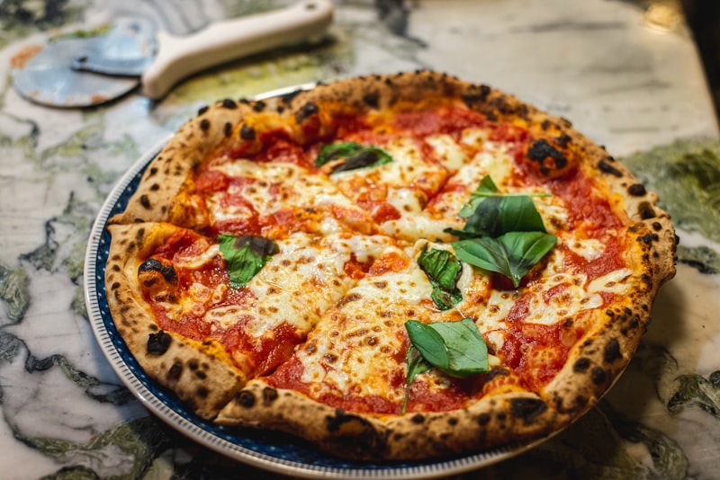 Pizza margherita napolitaine, mozzarella et basilic sur un plan de marbre