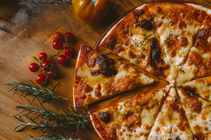Pizza dorée au four à bois, tomates cerises et romarin sur une table en bois