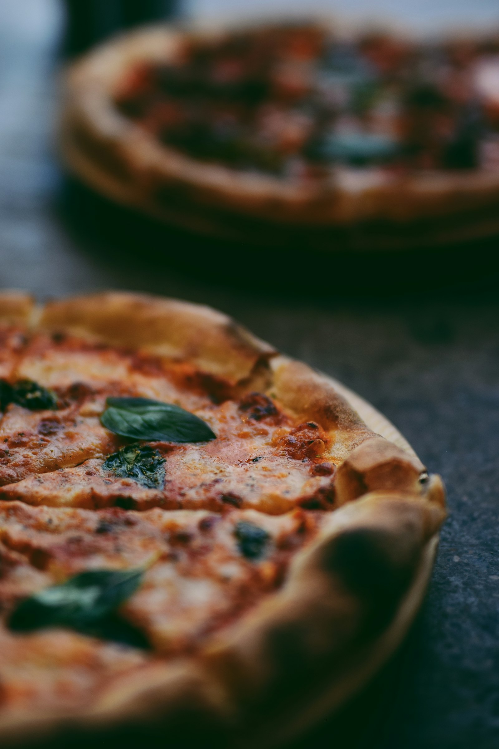 Deux pizzas napolitaines à la croûte soufflée et basilic frais, au sortir du feu de bois
