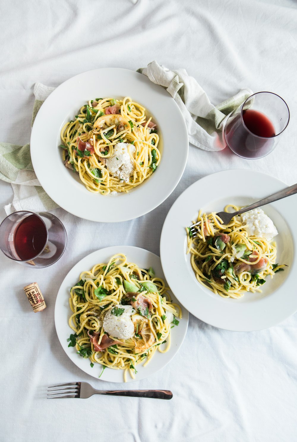 Table dressée pour le dîner, pâtes fraîches et verre de vin rouge